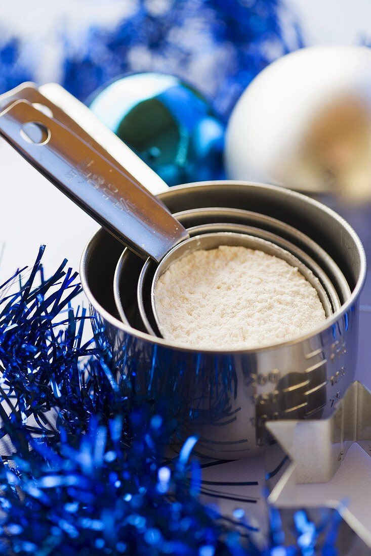 Various measuring cups with flour and Christmas decorations