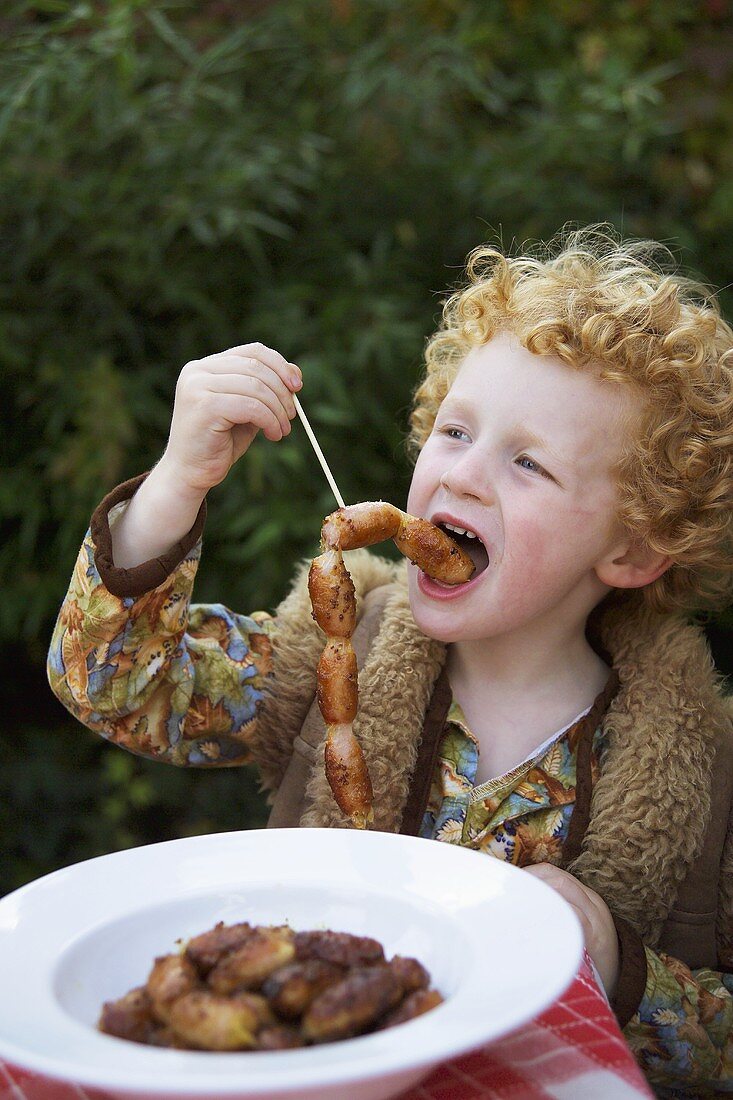 Small boy eating honey mustard sausage