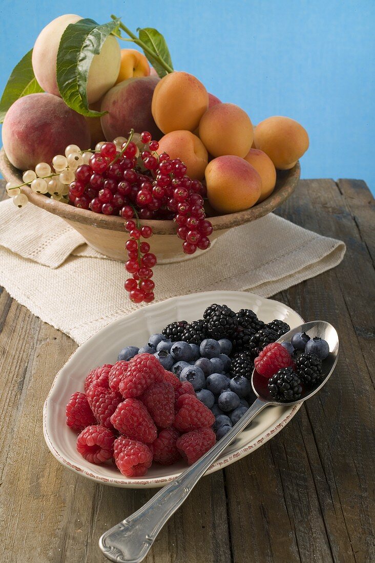 Bowl of mixed fruit and plate of berries