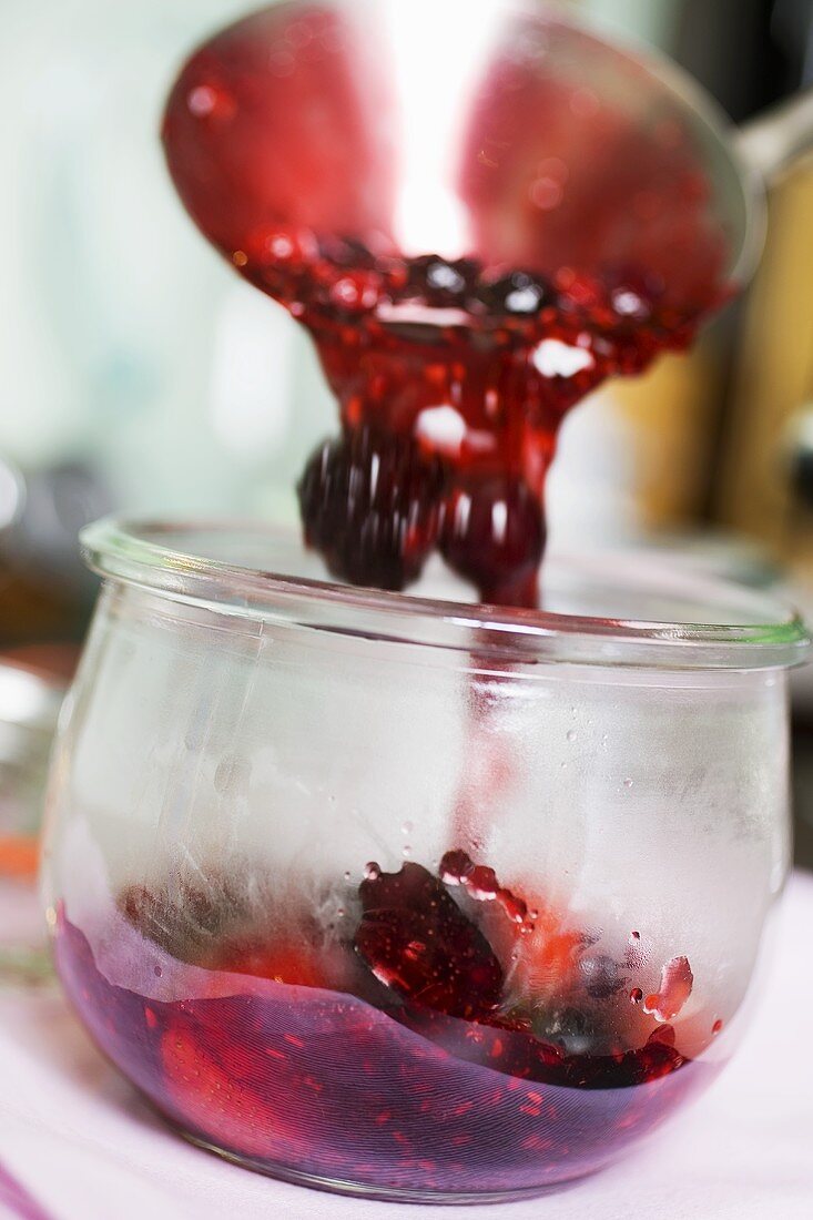 Ladling berry jam into a jar