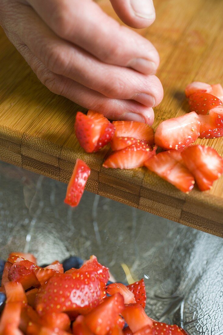 Pushing chopped strawberries off a board