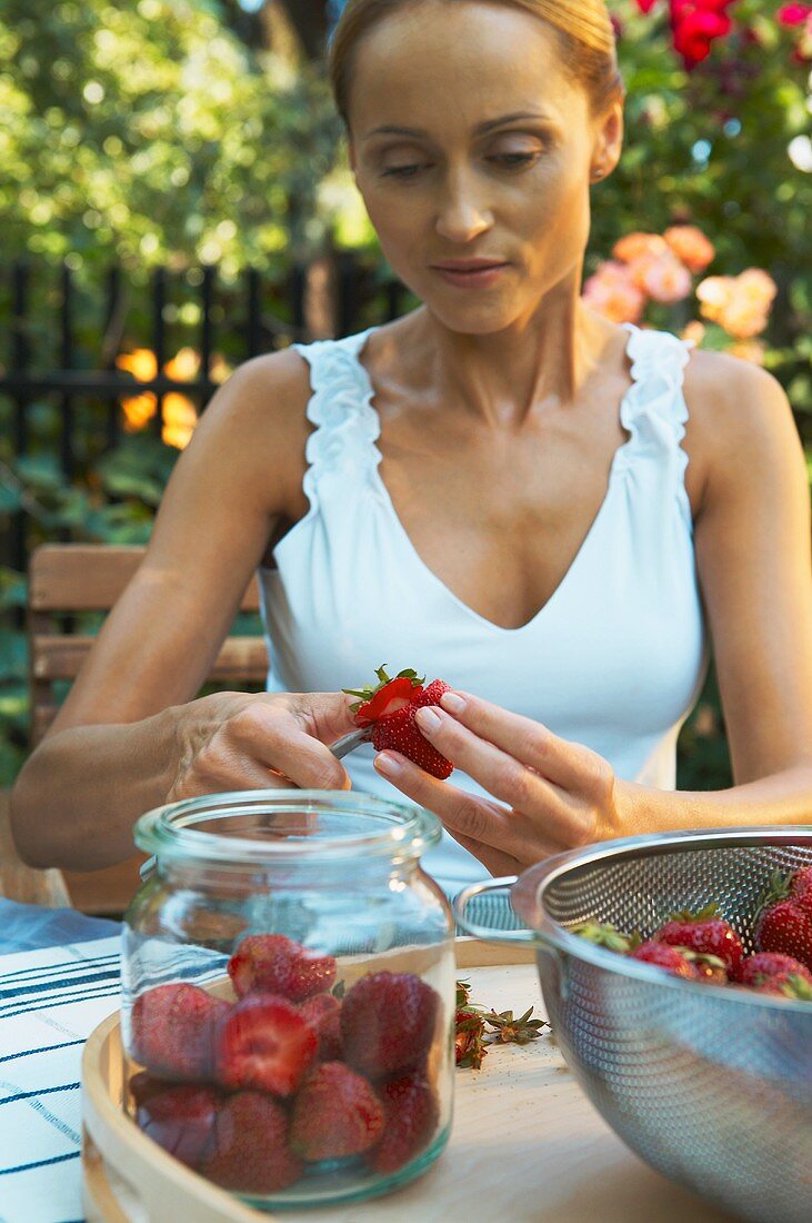 Frau putzt Erdbeeren im Garten