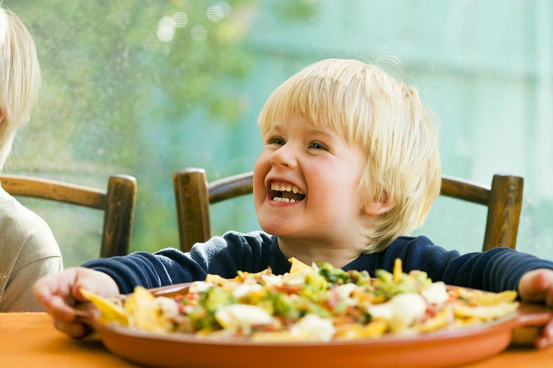 Lachender Junge & Nachos mit Tomatensalsa und Guacamole