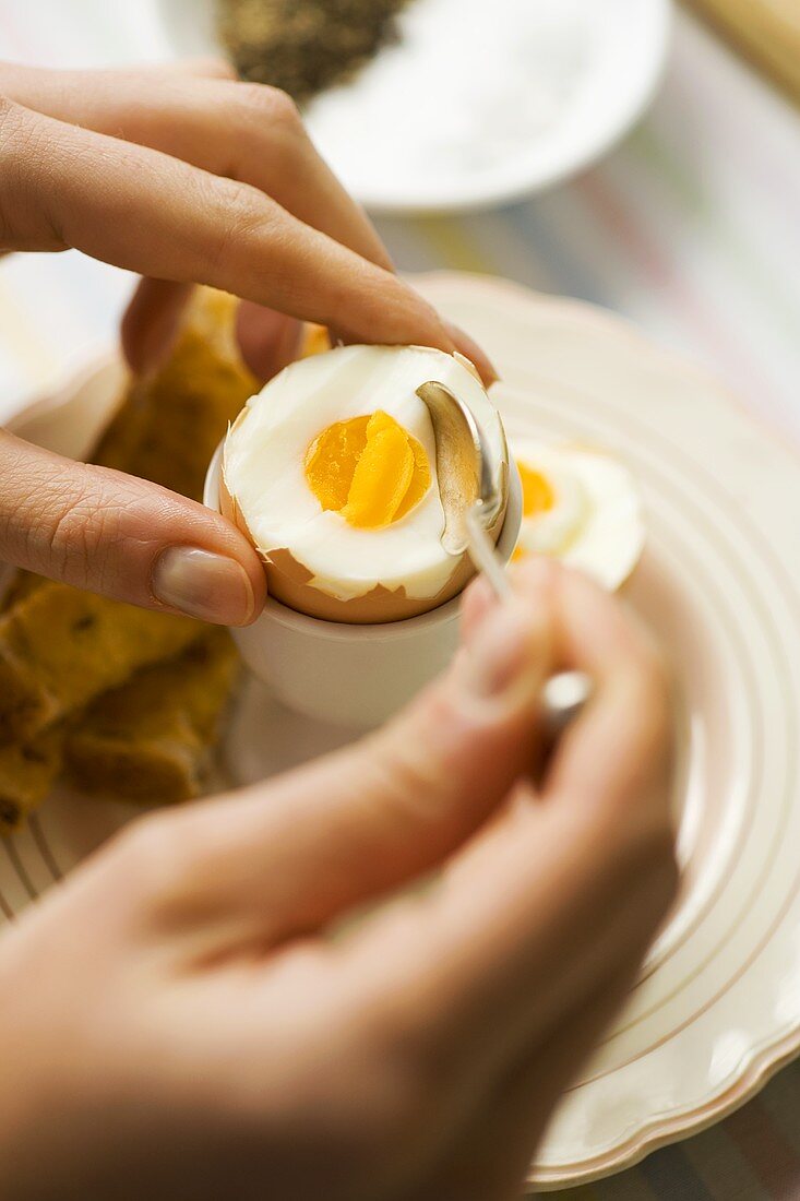 Ein gekochtes Ei mit Toast-Streifen essen