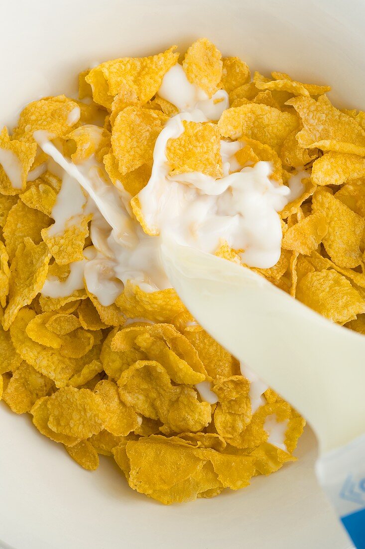 Milch über Cornflakes gießen