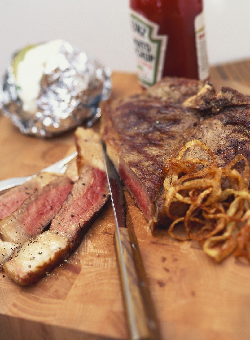 T-bone steak with baked potatoes and fried onions