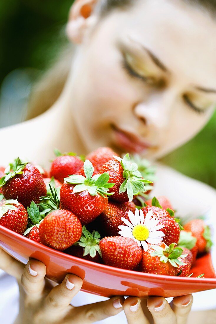 Junge Frau hält eine Schale Erdbeeren