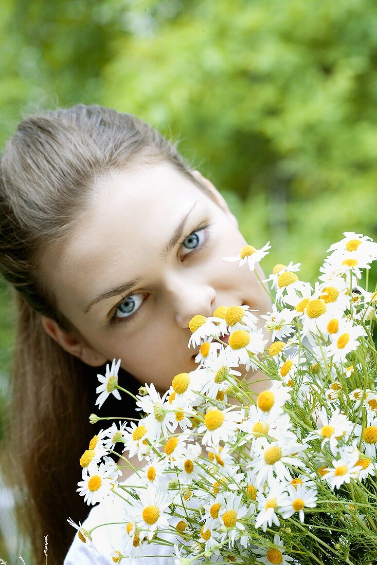 Young woman with a bunch of fresh chamomile