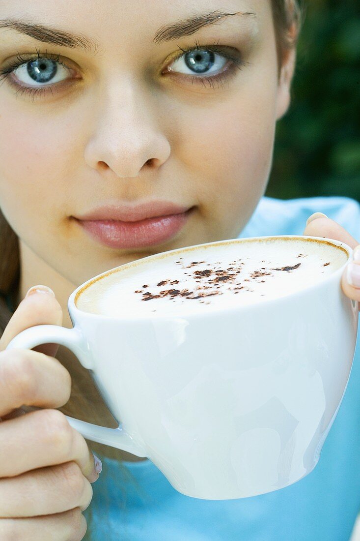 Junge Frau hält eine Tasse Cappuccino