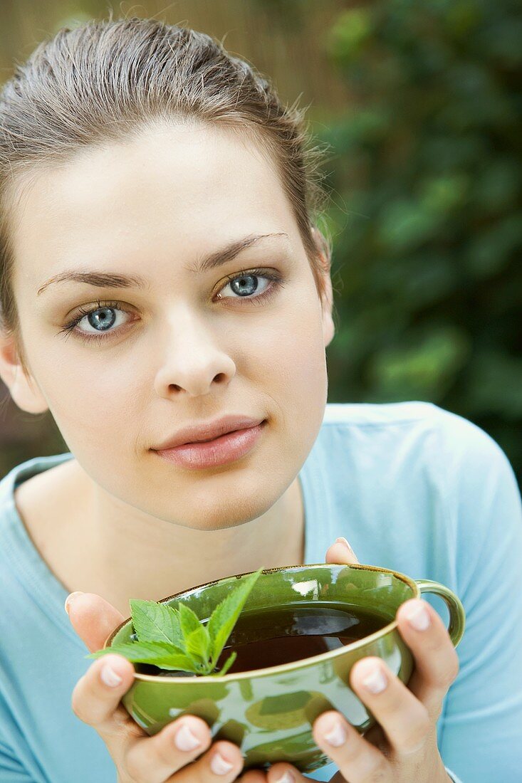 Young woman holding a cup of mint tea