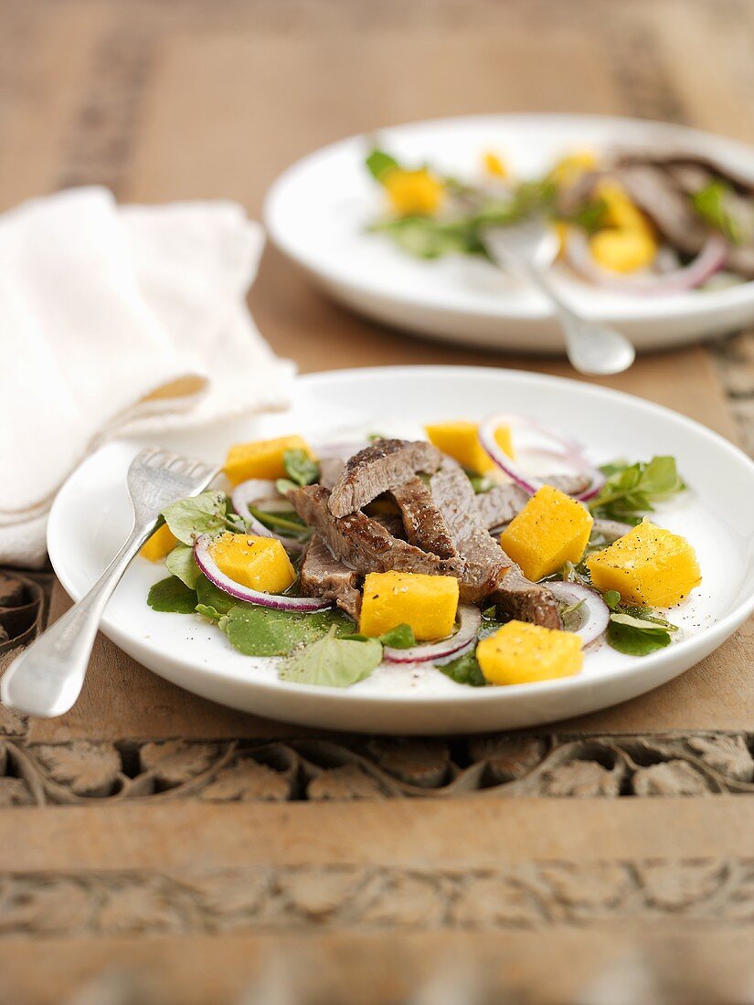 Fried beef steak on mango salad