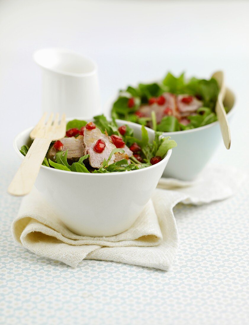 Salad leaves with roast duck breast and pomegranate seeds