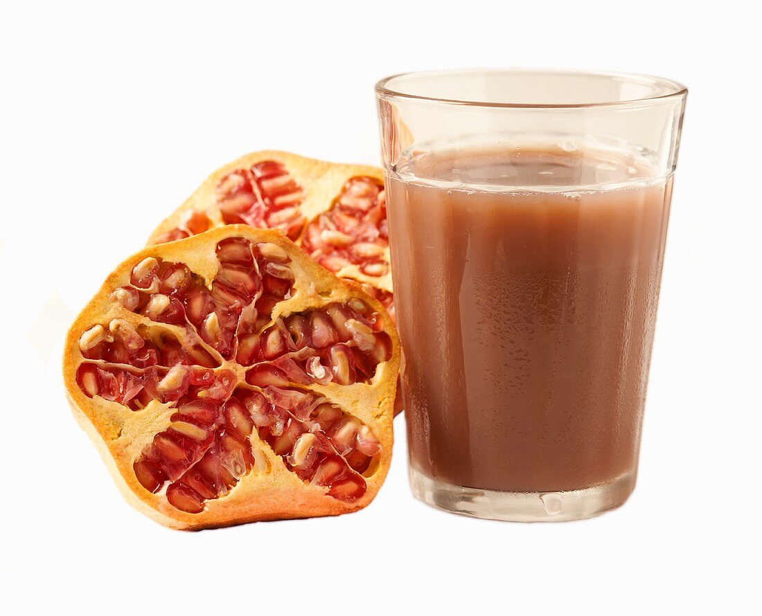 Glass of pomegranate juice and halved pomegranate