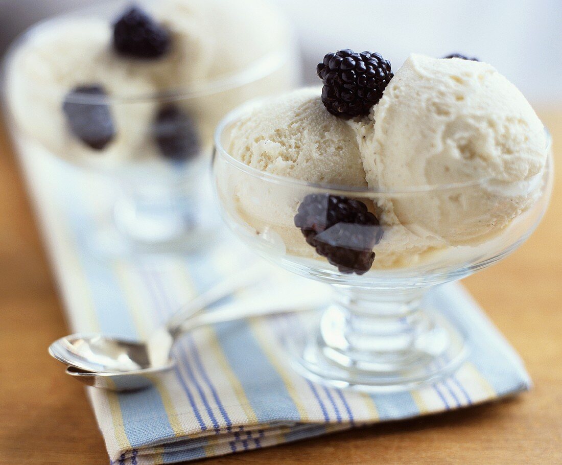 Two glasses of vanilla ice cream with blackberries