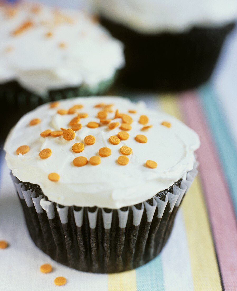 Chocolate muffin with icing and orange sprinkles
