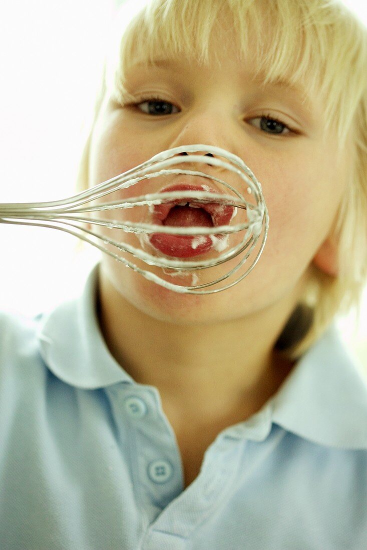 Small boy licking whisk
