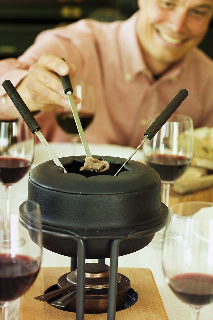 Mann mit Fonduespiess beim Fondue essen