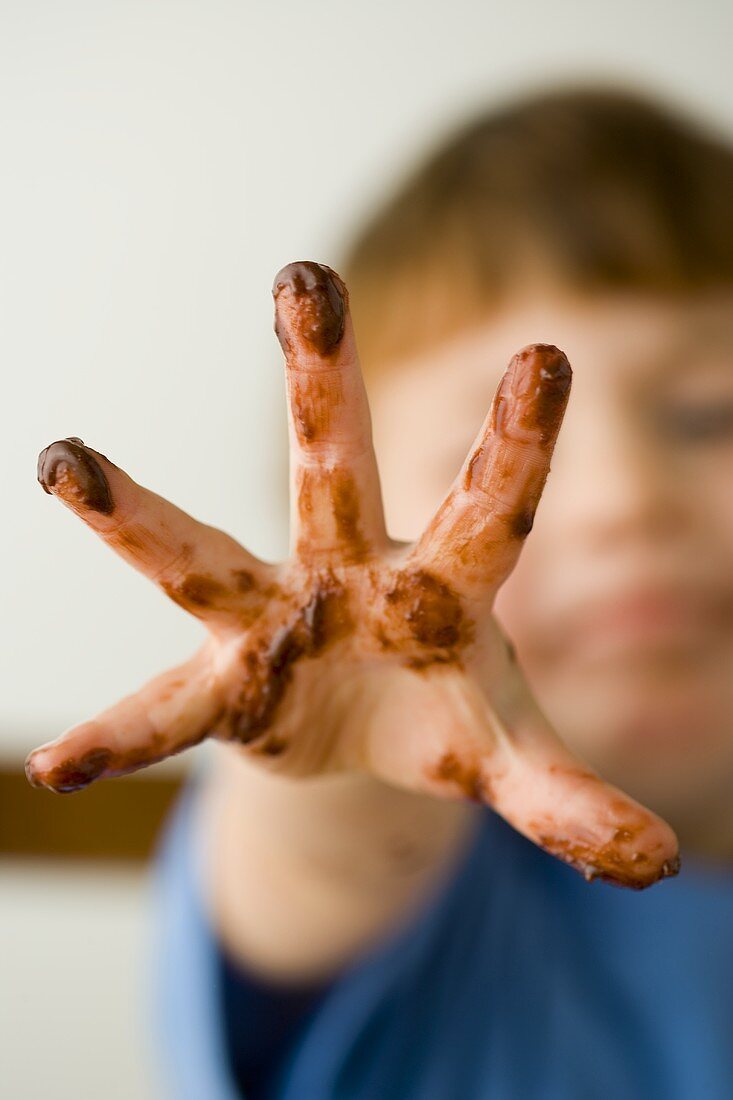Kleiner Junge mit Schokoladen-Hand