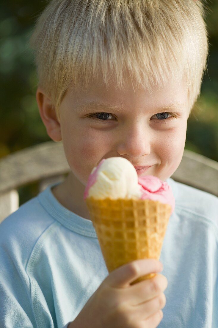 Small boy holding strawberry and vanilla ice cream cone