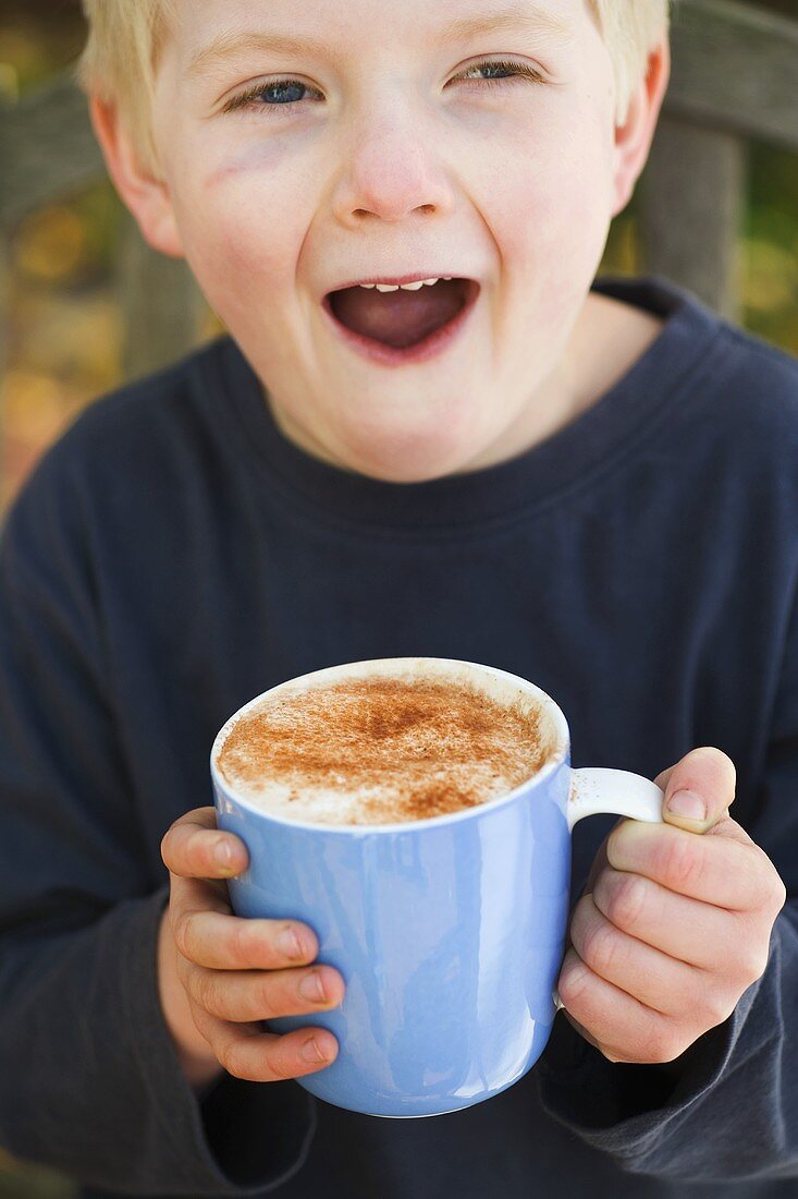 Junge hält Tasse mit heißer Schokolade