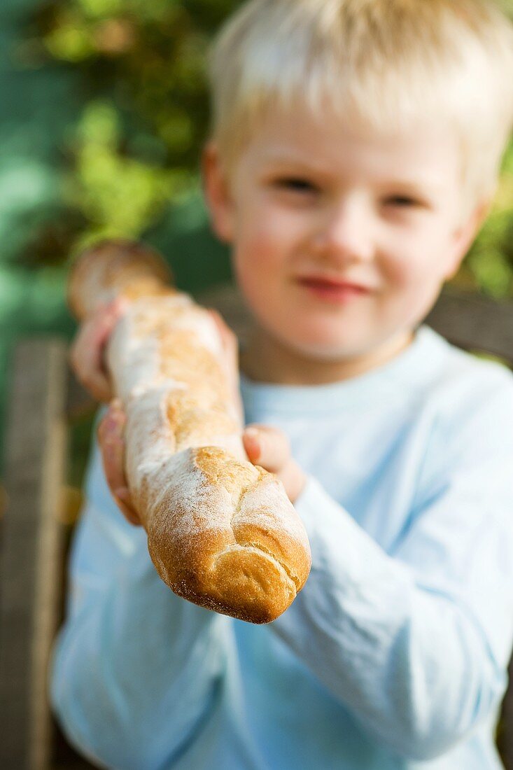 Blond boy holding a baguette stick