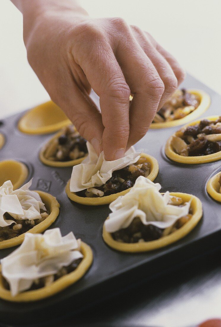 Putting filo pastry on top of mincemeat tarts