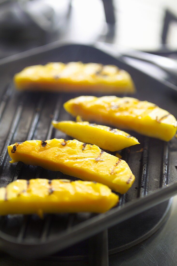 Grilling slices of mango in grill pan