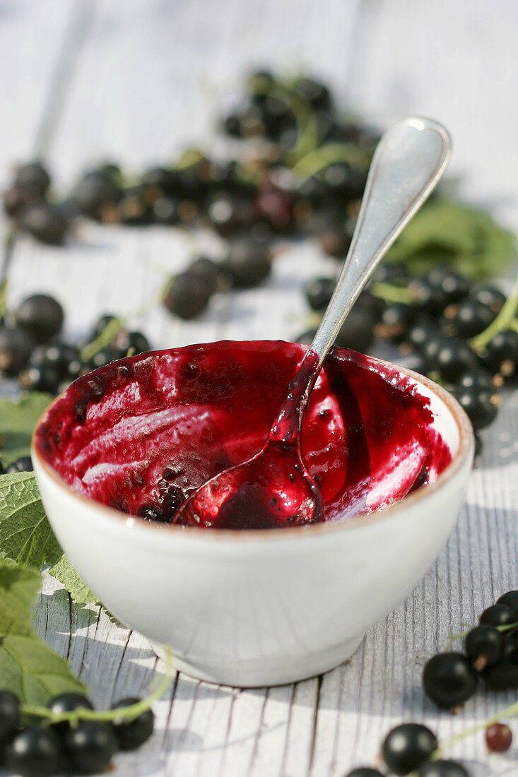 Blackcurrant jam in small bowl with spoon