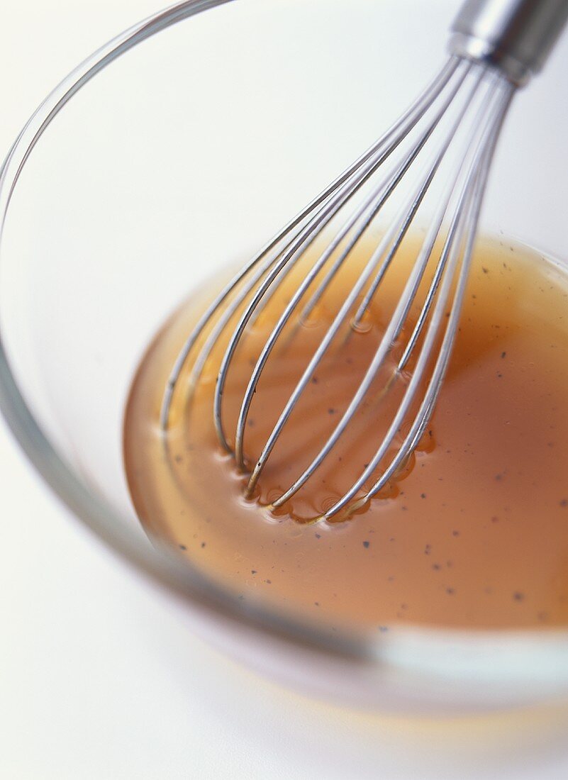 Vinaigrette in a glass bowl with whisk