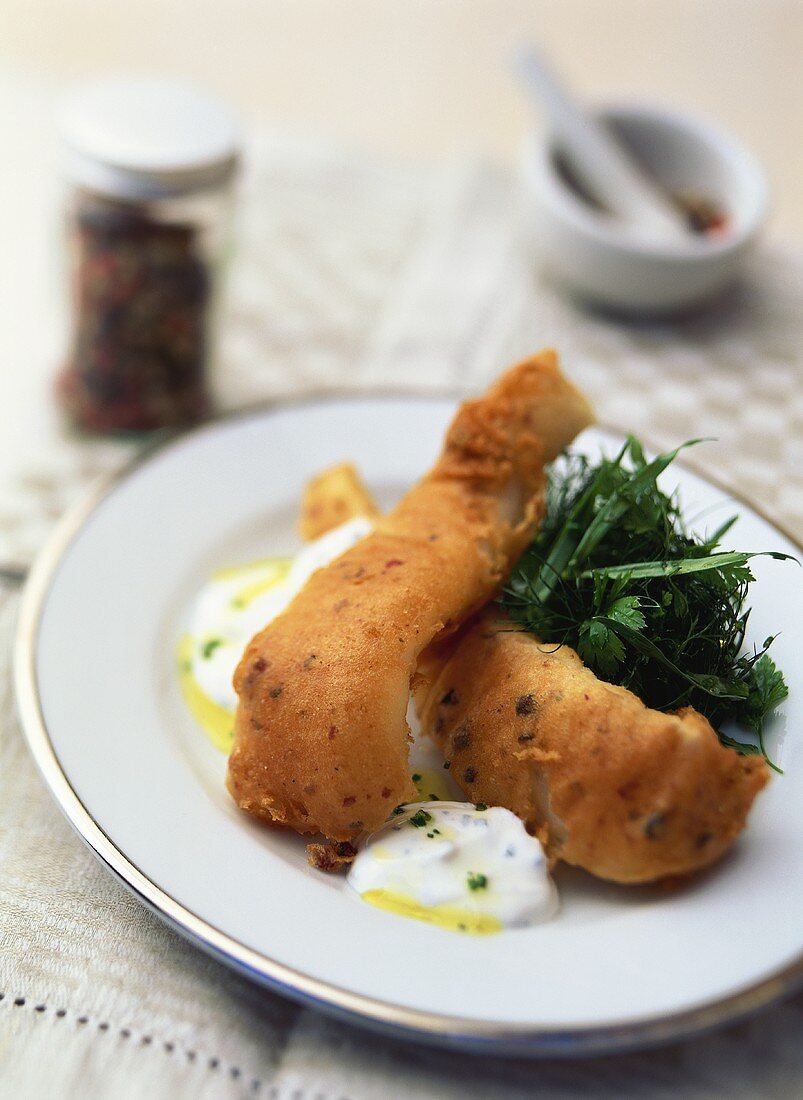 Strips of salmon in pepper batter with herb salad