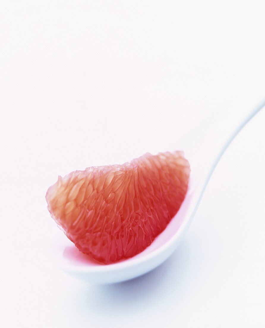 Grapefruit segment on white spoon