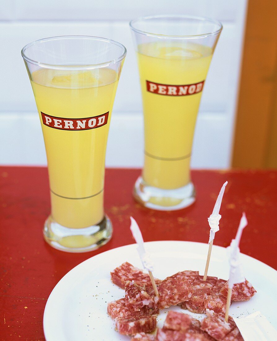 Two glasses of Pernod and salami appetisers