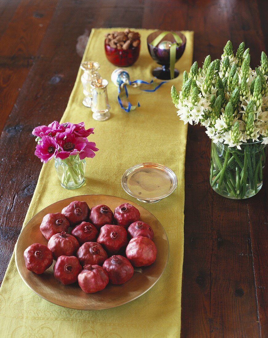 Granatäpfel in einer Schale auf Tisch mit Blumendeko