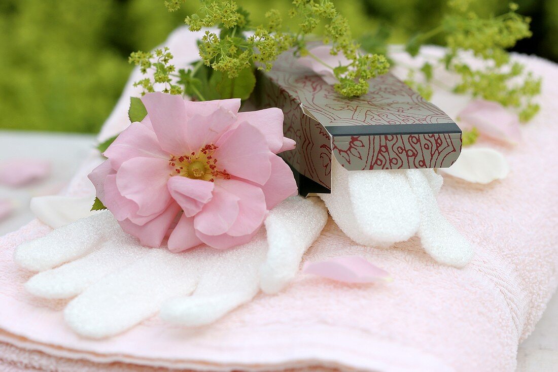 Peelinghandschuh auf Handtüchern mit Rosenblüte