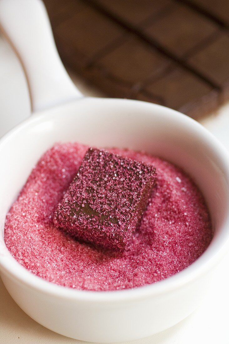 Schoko-Nougat-Praline in rosa Zucker tauchen