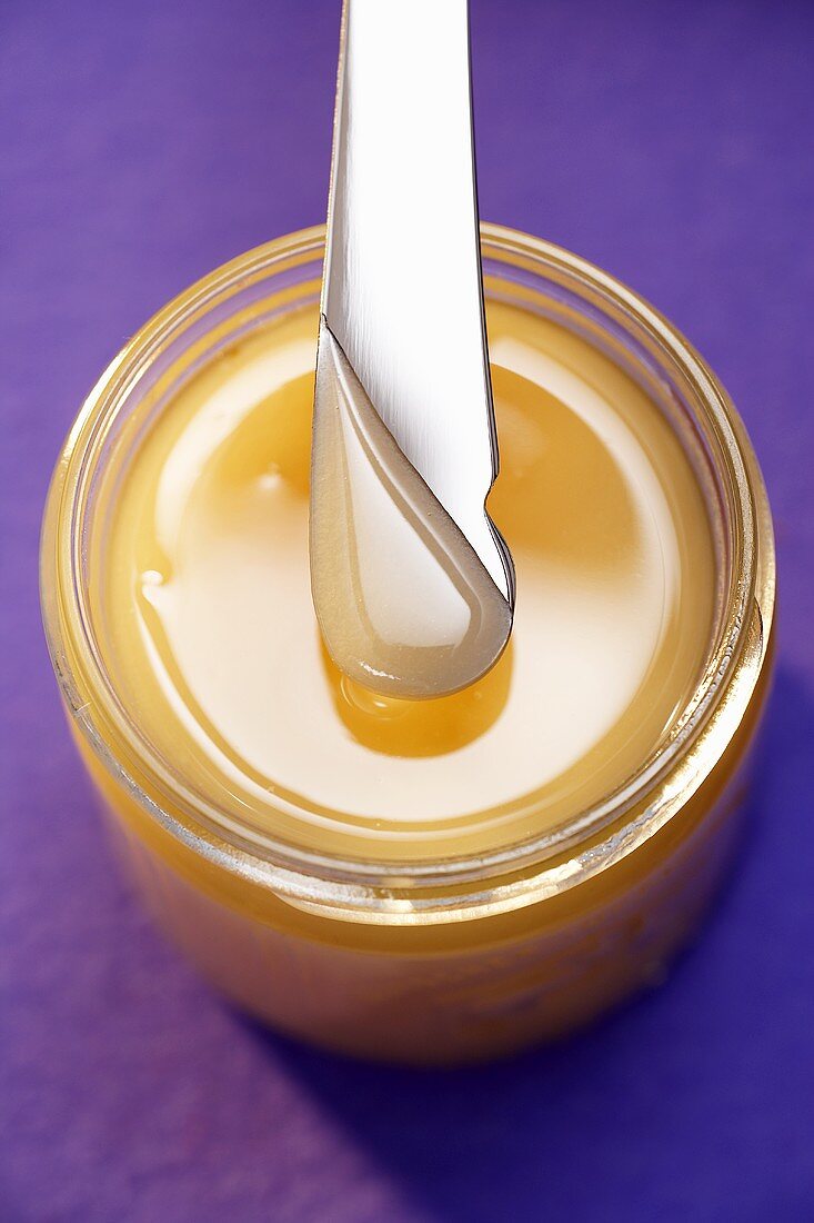 Creamy honey in a jar with a knife