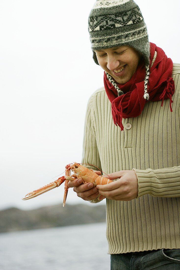 Young man holding a Norway lobster in his hands