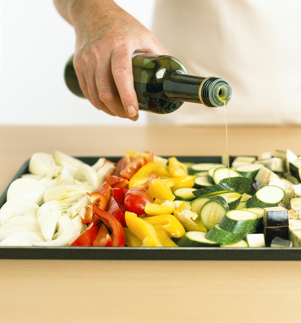 Roasted vegetables: pouring olive oil over vegetables