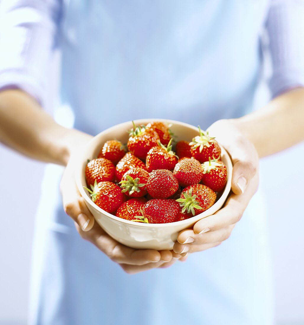 Frau hält ein Schälchen mit frischen Erdbeeren