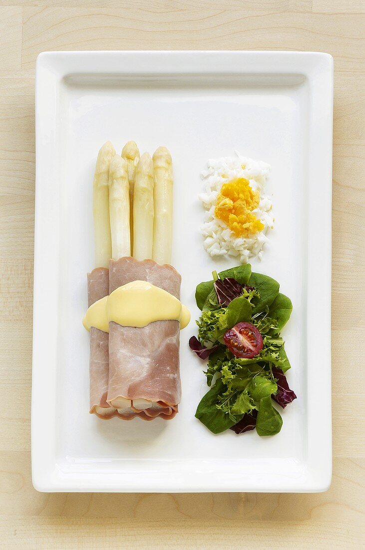 White asparagus wrapped in ham, salad leaves & chopped egg