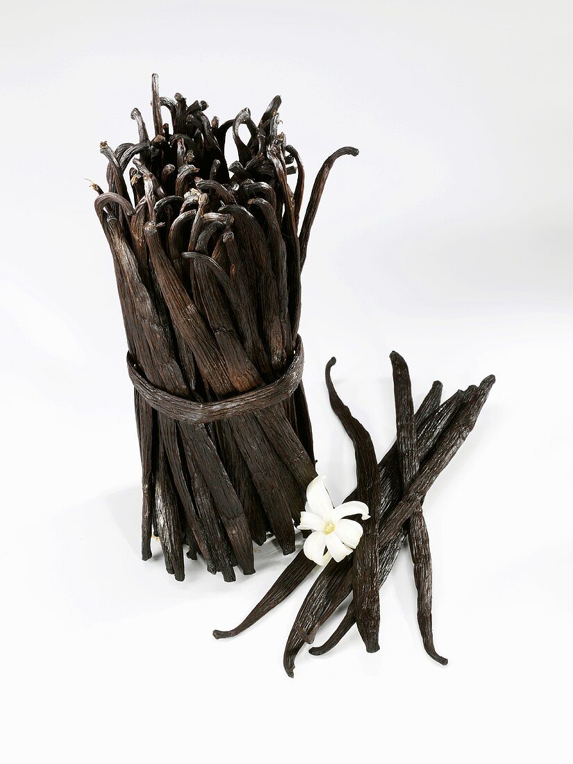 A bundle of vanilla pods and individual pods with flower