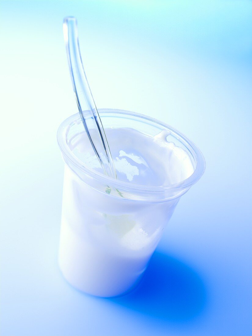 A half-full yoghurt pot with spoon