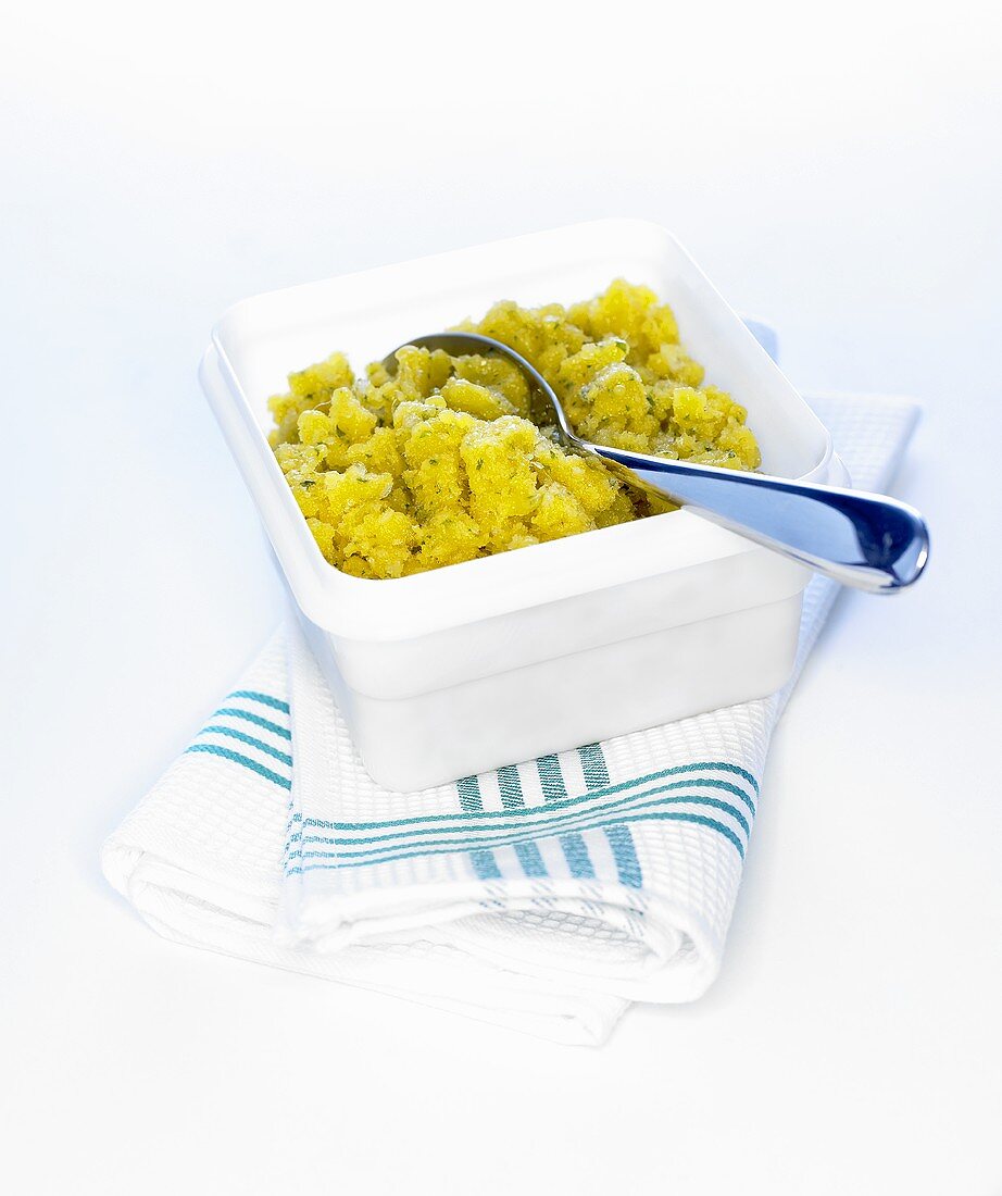 Pineapple sorbet in a plastic box with spoon
