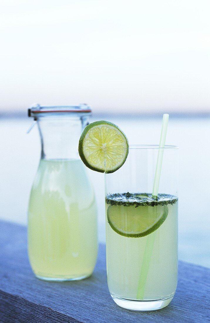 Lime drink in bottle and glass with straw