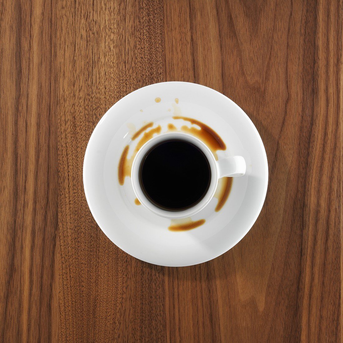 A cup of coffee, partly spilt into saucer