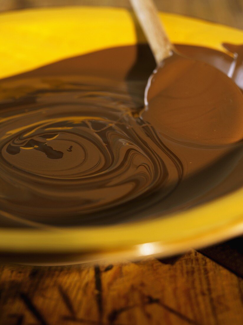 Melted chocolate with wooden spoon in a dish
