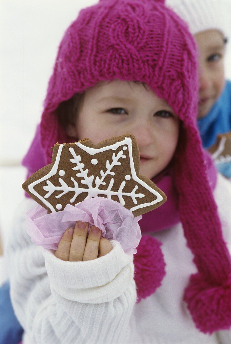 Small child holding gingerbread star in her hand