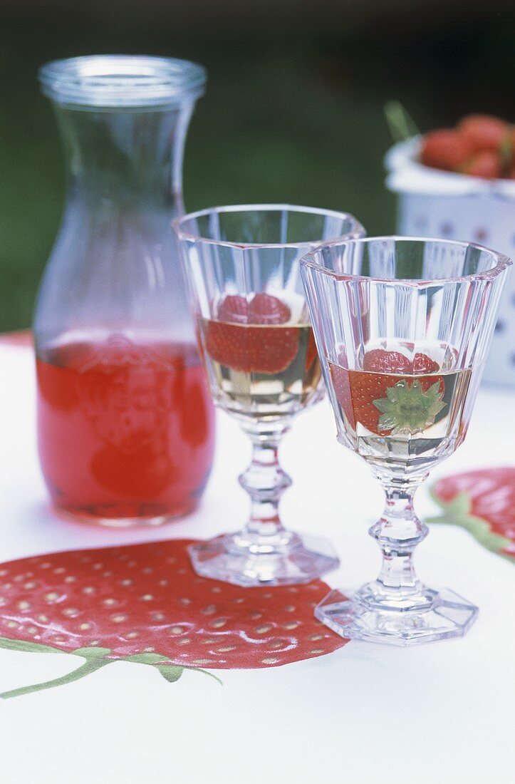 Zwei Gläser Erdbeerwein auf einem Tisch im Garten