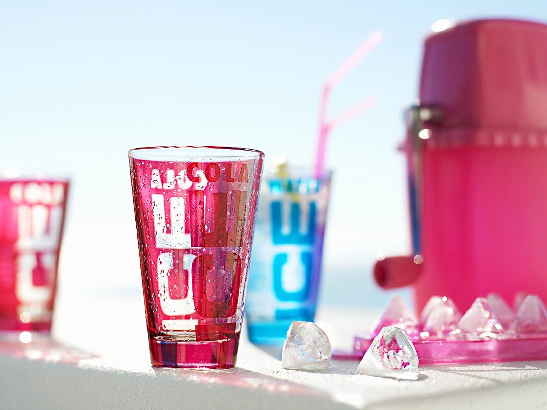 Coloured glasses with ice cubes and ice crusher