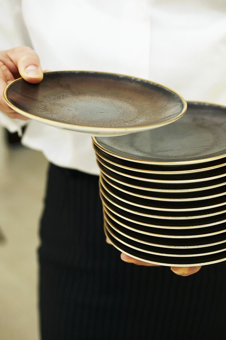 Waiter carrying a pile of plates